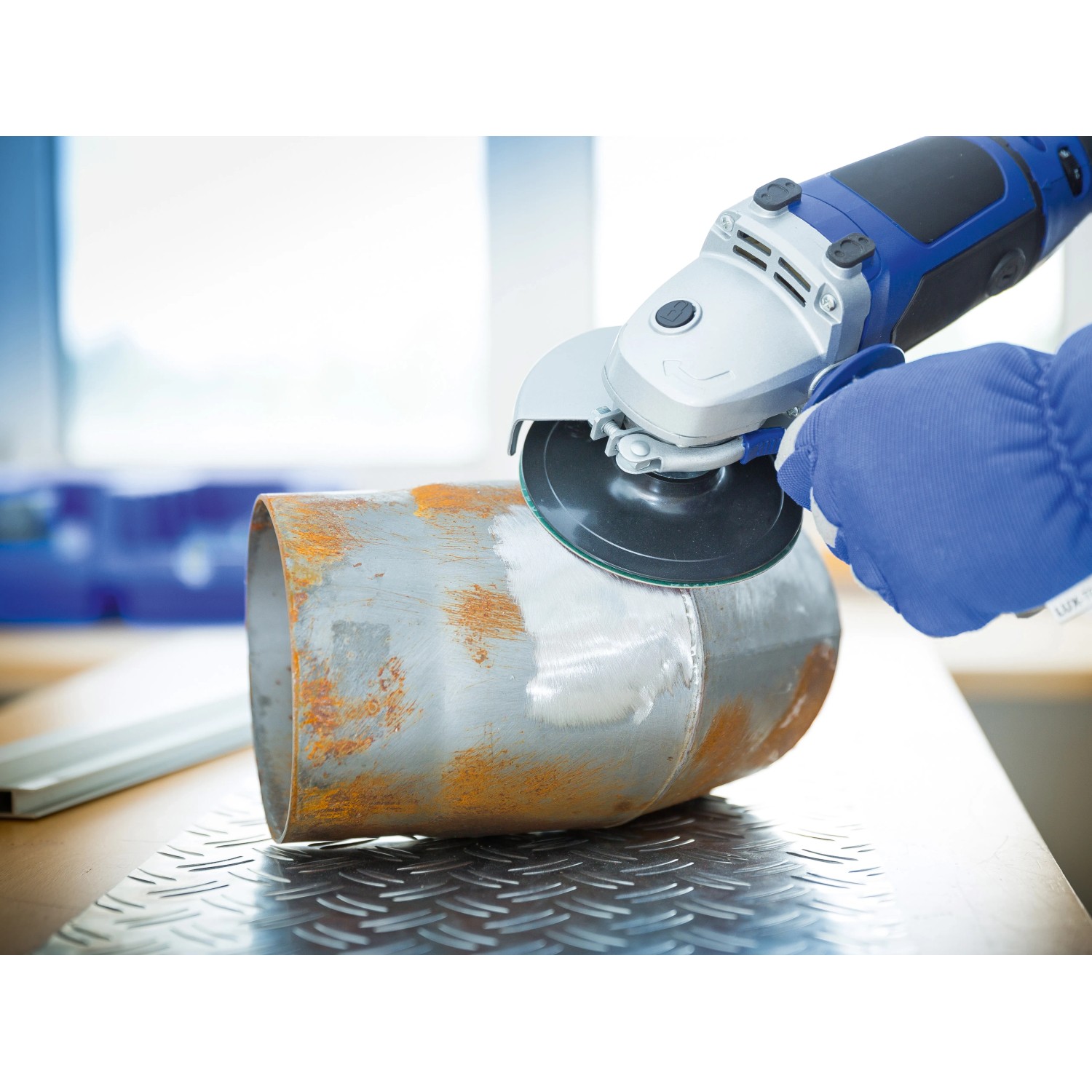 LUX Fiberscheibe Classic im Einsatz: Winkelschleifer beim Entrosten eines Metallrohrs.