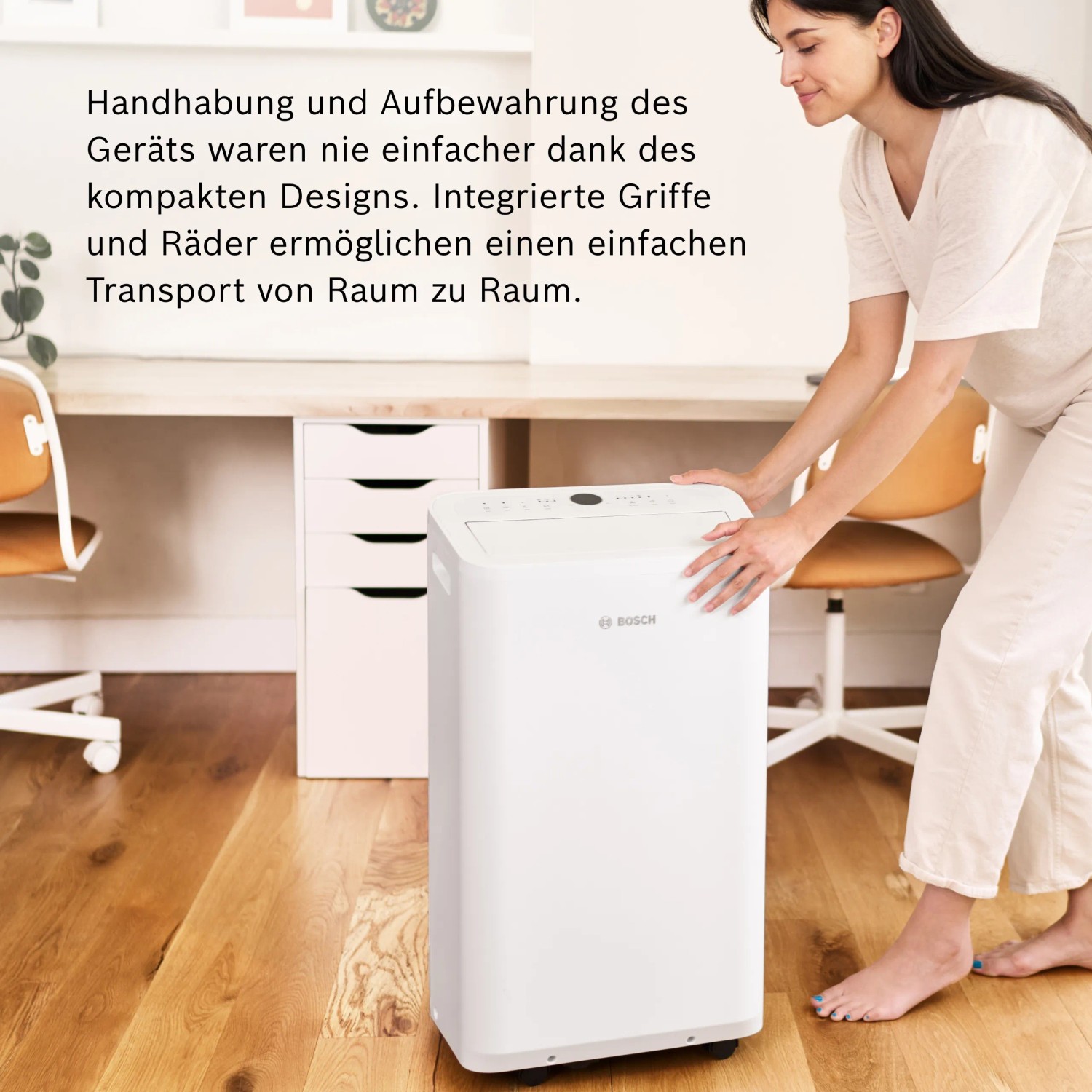 Frau schiebt weißes Bosch Klimagerät Cool 2000 (2,6 kW, 35 m²) im Büro.