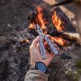 Gerber Multi-Tool Suspension Nxt in Hand vor Lagerfeuer. Kompaktes Multitool mit Zange.