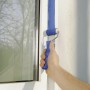 Hand streicht mit LUX Goldfadenwalze (5 cm) blaue Farbe an eine Wand neben einem Fenster.