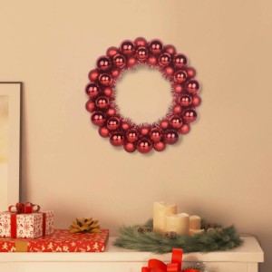 Glänzender roter Weihnachtsballkranz aus Polystyrol an Wand. Festliche Dekoration für die Feiertage.