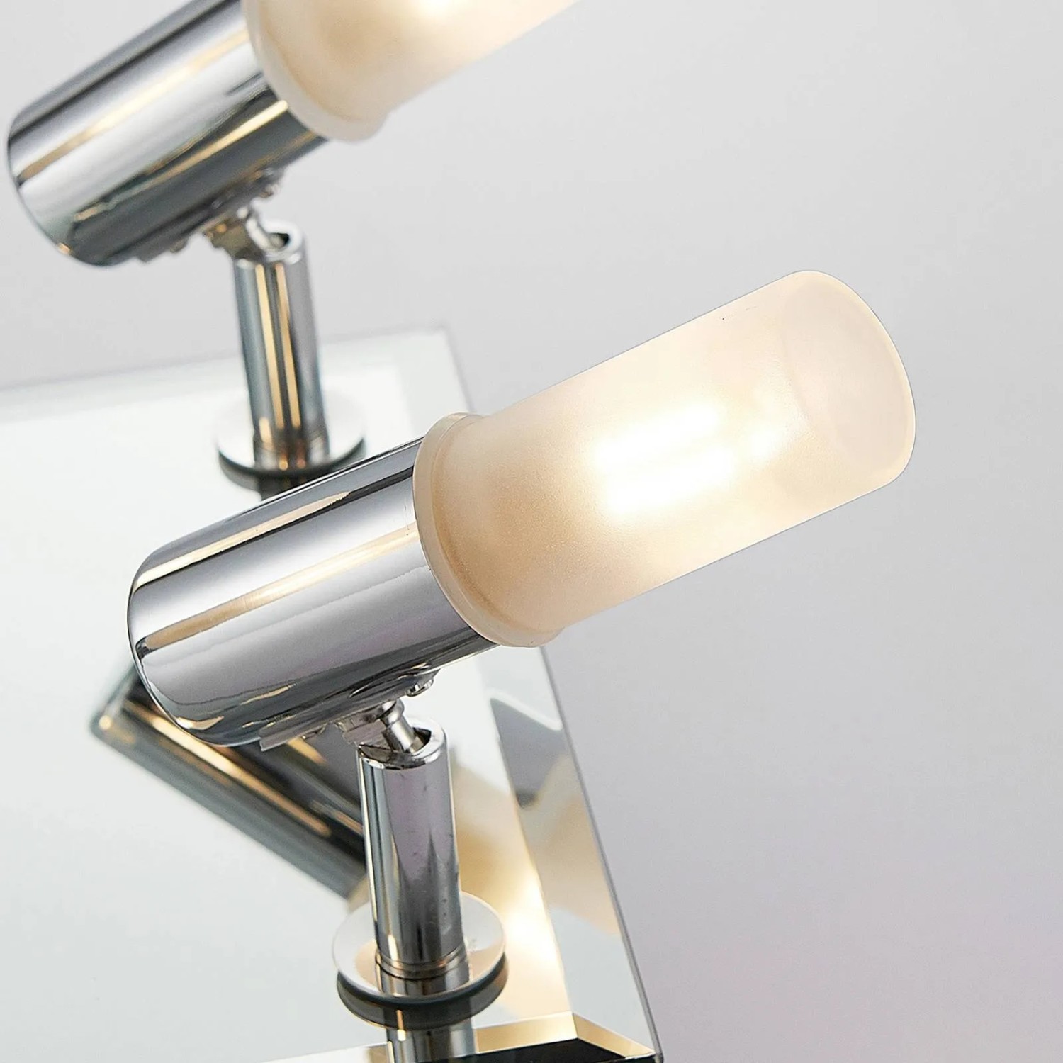 Lindby Zela Bad-Deckenleuchte in Chrom. Nahaufnahme von zwei modernen, 4-flammigen G9 Leuchtenköpfen aus Metall mit Glasdiffusoren.