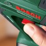 Detailaufnahme: Hand betätigt roten Schalter am grünen Bosch 18V Akku-Bohrhammer Uneo Maxx.