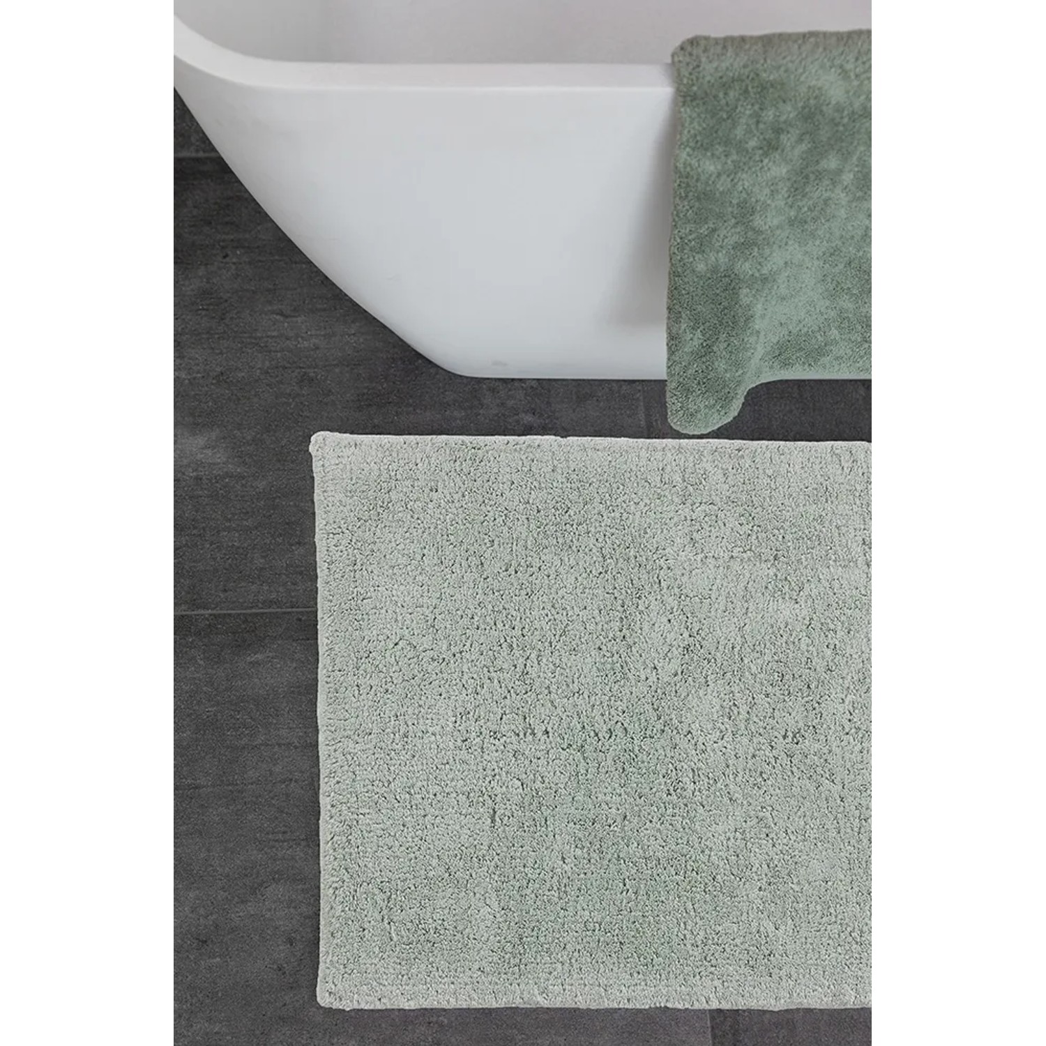 Schöner Wohnen Badteppich Bahamas in Mint, 67x110 cm, vor Badewanne auf grauem Boden.