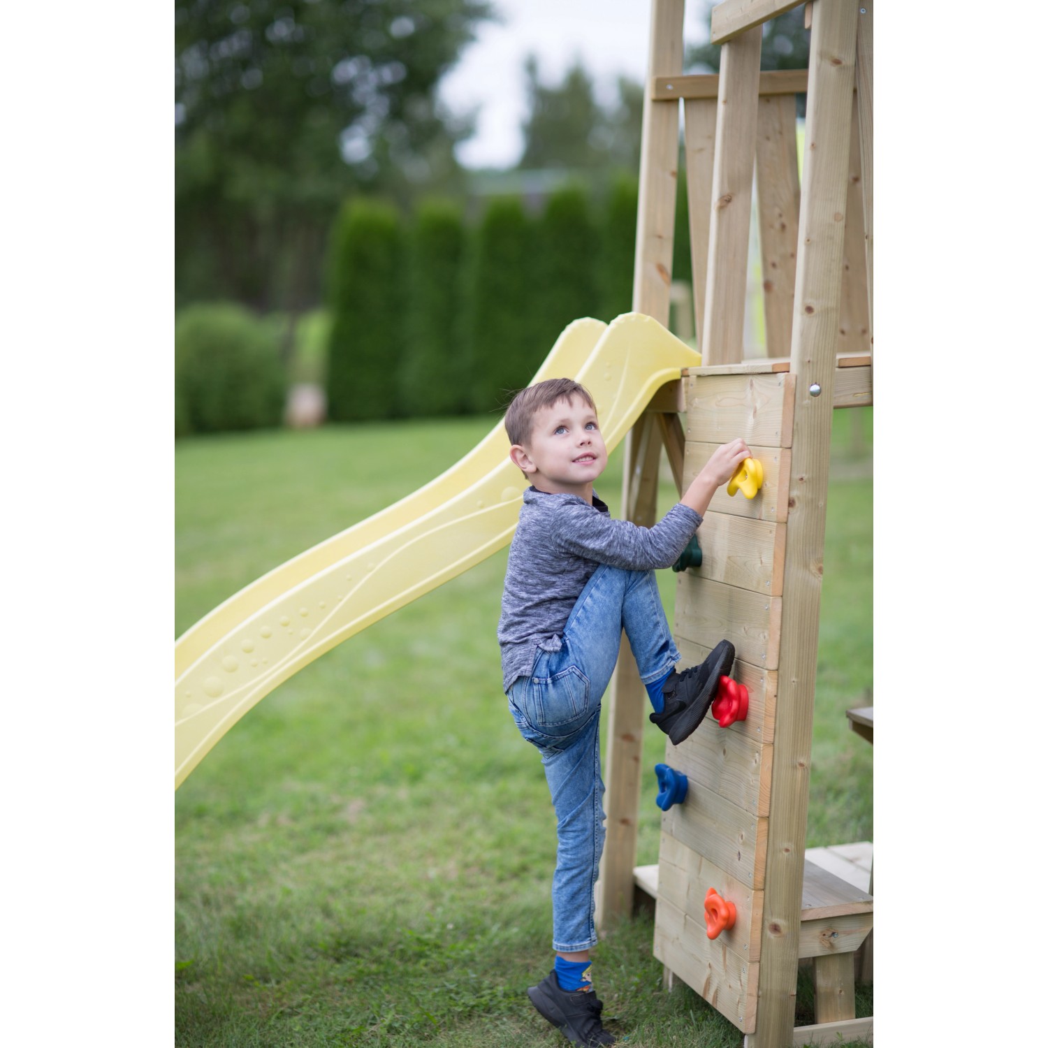 Kind klettert auf Spielturm Giraffe mit Rutsche und Kletterwand im Garten.