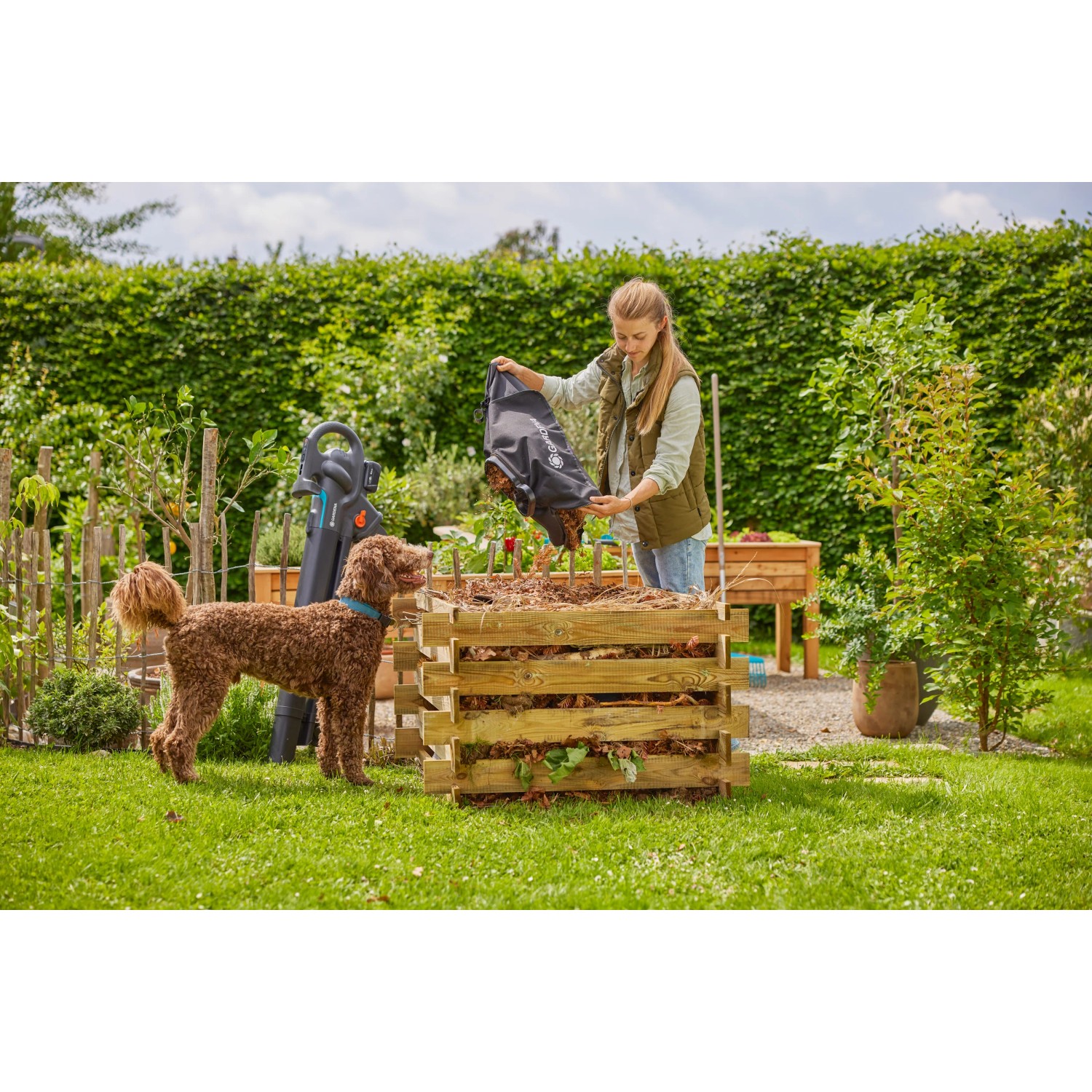 Frau leert Laubsack in Kompost, Gardena Laubsauger im Hintergrund. PowerJetCollect für Gartenarbeit.