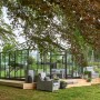 Juliana Gewächshaus Grand Oase 18 Anthrazit mit Sitzgruppe auf Holzterrasse im Garten.