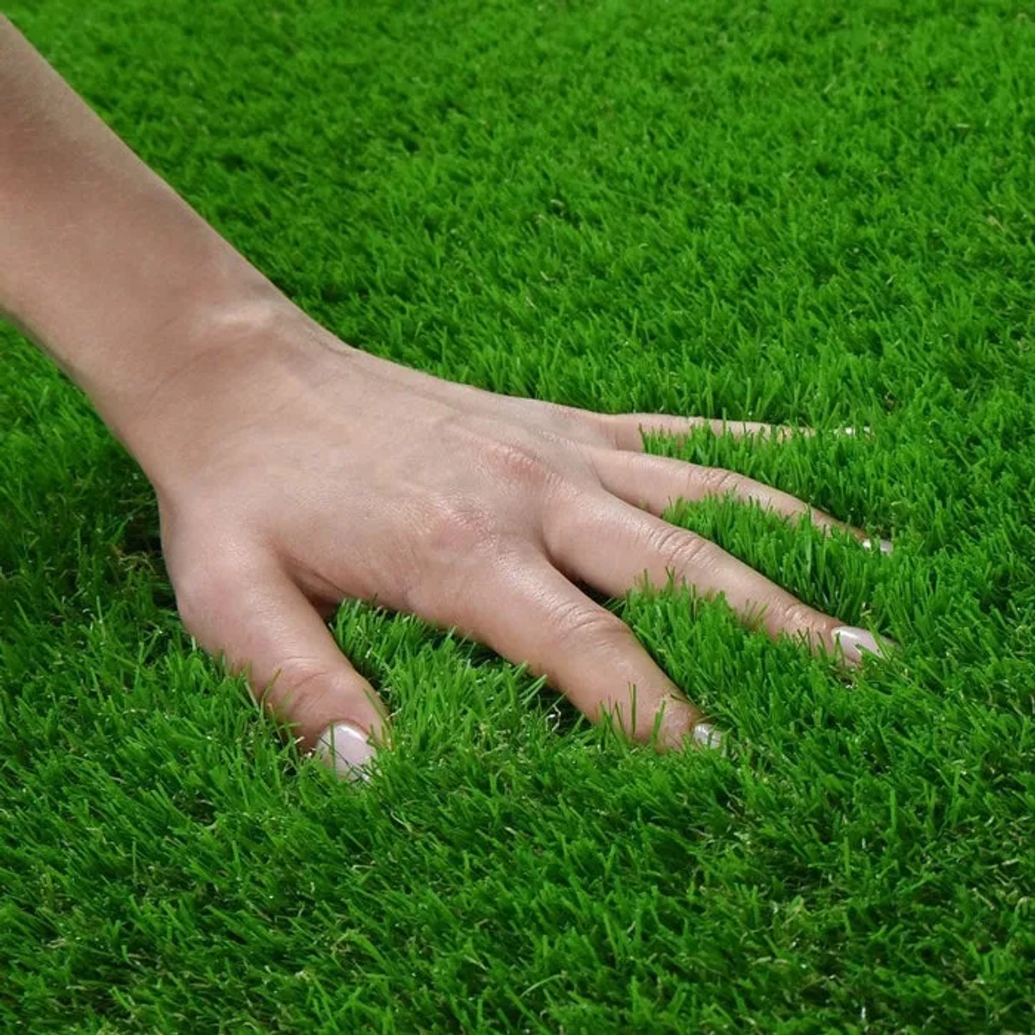Nahaufnahme: Hand berührt weichen, grünen Karat Kunstrasen Vita (40mm). Ideal für Garten, Balkon & Terrasse.