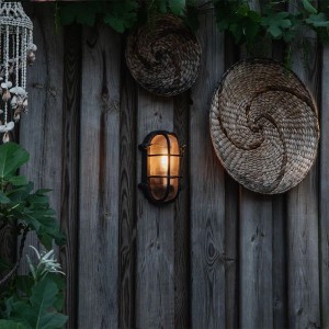Schwarze, ovale Wand- und Deckenleuchte Noutica im Industrie-Stil an Holzwand.
