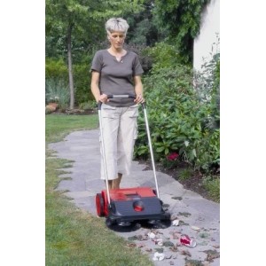 Frau benutzt Starmix Haaga 255 Kehrmaschine auf einem Gartenweg, um Blätter und Müll zu entfernen.