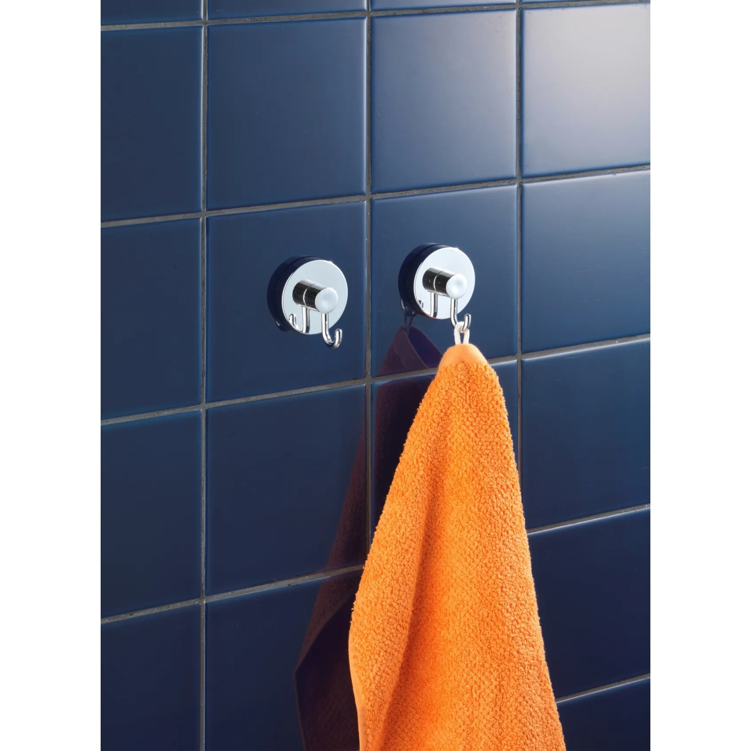 Wenko Vacuum-Loc Hakenset, 2 Chrom-Haken an blauer Wand, einer mit orangefarbenem Handtuch.