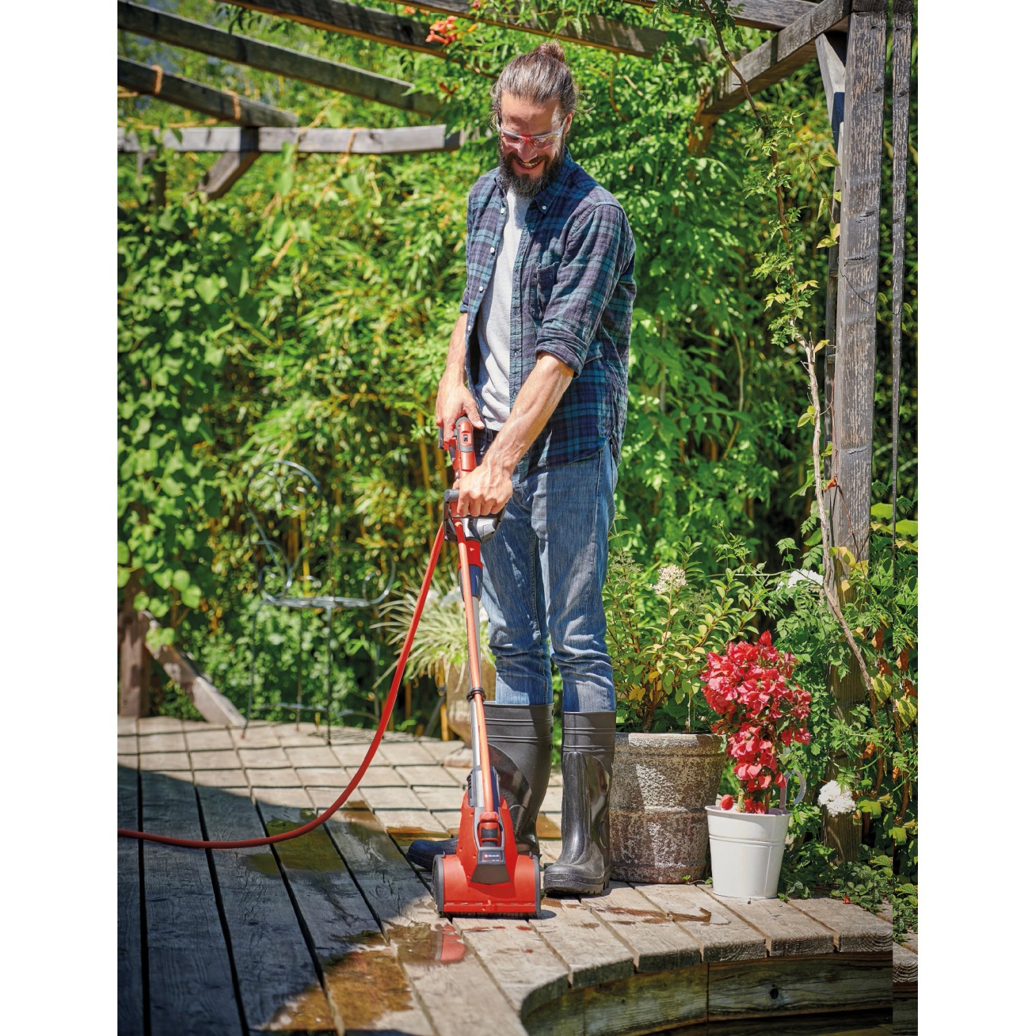 Mann reinigt Holzterrasse mit Einhell Akku-Oberflächenbürste PICOBELLA 18/215. Inkl. Gartenschlauchanschluss.