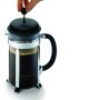 Hand drückt Kolben des Bodum Caffettiera French Press Kaffeebereiters. Glas, schwarzer Deckel, Chromrahmen. Für aromatischen Kaffee.