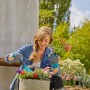 Frau pflanzt Blumen mit Gardena Gartenhandschuhen (Größe L).