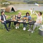 Schwarzer WOLTU Klapptisch Gartentisch mit Metallbeinen, klappbar, am Seeufer. Vier Personen genießen ein Picknick im Freien.
