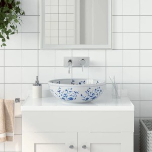 Rundes Aufsatzwaschbecken in Weiß und Blau mit floralem Muster auf einem weißen Waschtisch.