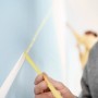 Anwendung von Tesa Malerband Professional (25mm) zum Abkleben einer Wand für präzise Farbkanten.