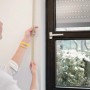 Frau misst mit beigem Schellenberg Rollladengurt Maxi die Fensterhöhe.