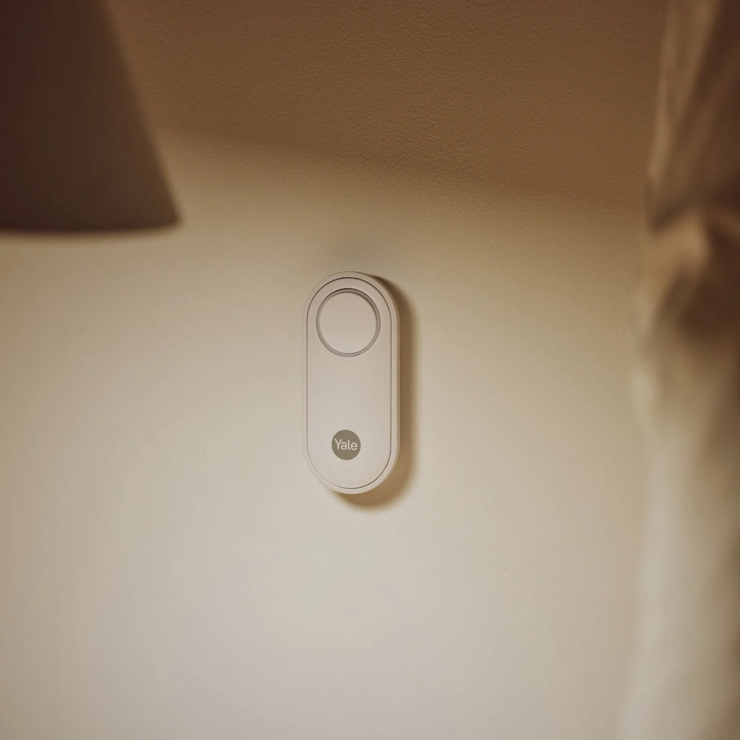 Weißer Yale Panikknopf/Türklingel für Smart Alarmanlage an Wand montiert.