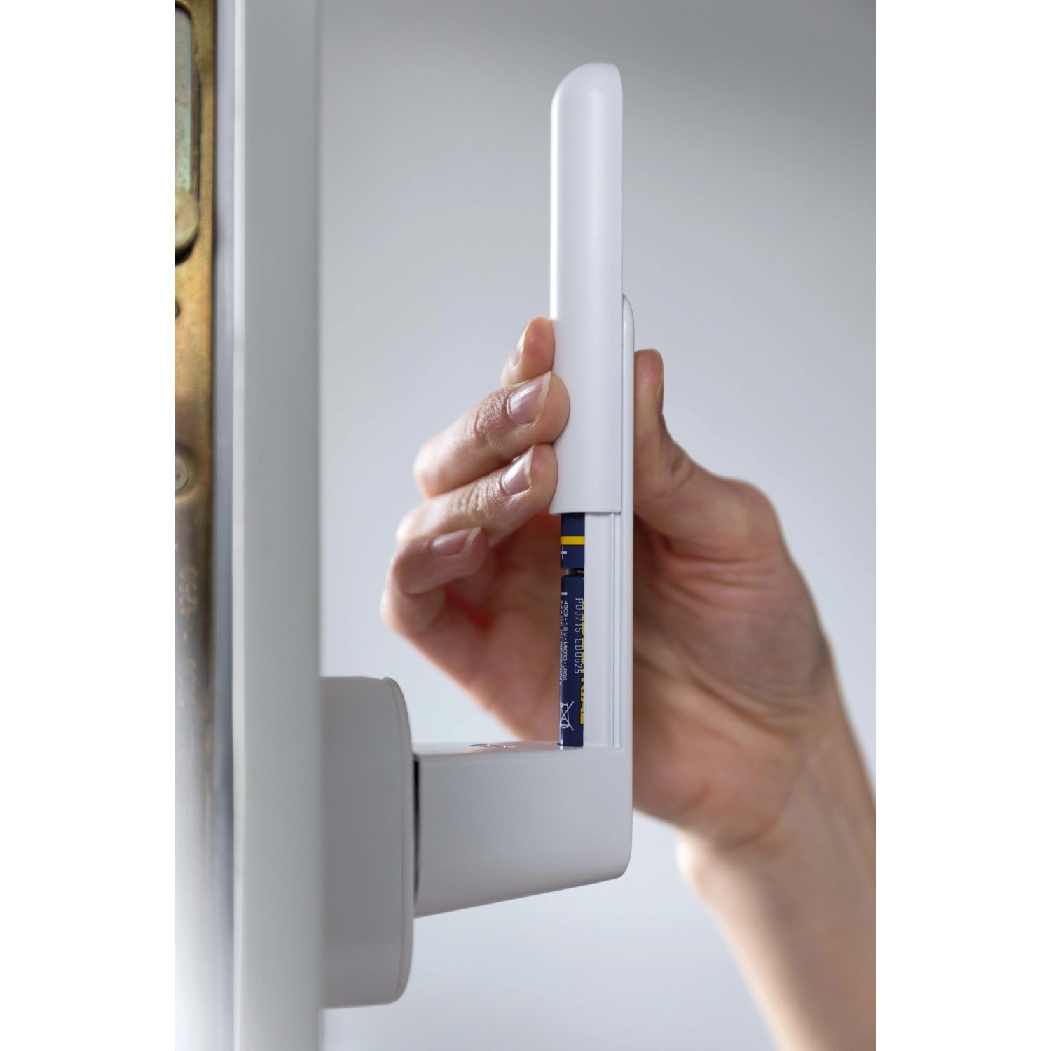 Weißer Schellenberg Sicherheits-Alarmgriff 37 mm mit Hand beim Einlegen der Batterie.