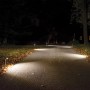 Braunfarbene Mr. Beams LED-Wegeleuchten mit Bewegungsmelder beleuchten einen dunklen Gartenweg.