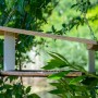 Dobar Vogelfutterhaus Futura II aus Holz mit Futterstation und Metallkette im Garten.