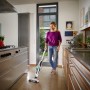 Frau saugt mit dem Leifheit Akku-Staubsauger Regulus PowerVac den Küchenboden.