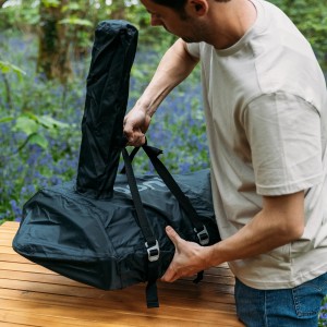 Ooni Karu 12 Transportabdeckung: Person packt den Grill in die schwarze, wasserdichte Tragetasche.