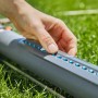 Gardena AquaZoom S Viereckregner in Nutzung: Hand stellt Düsen ein für präzise Rasenbewässerung.