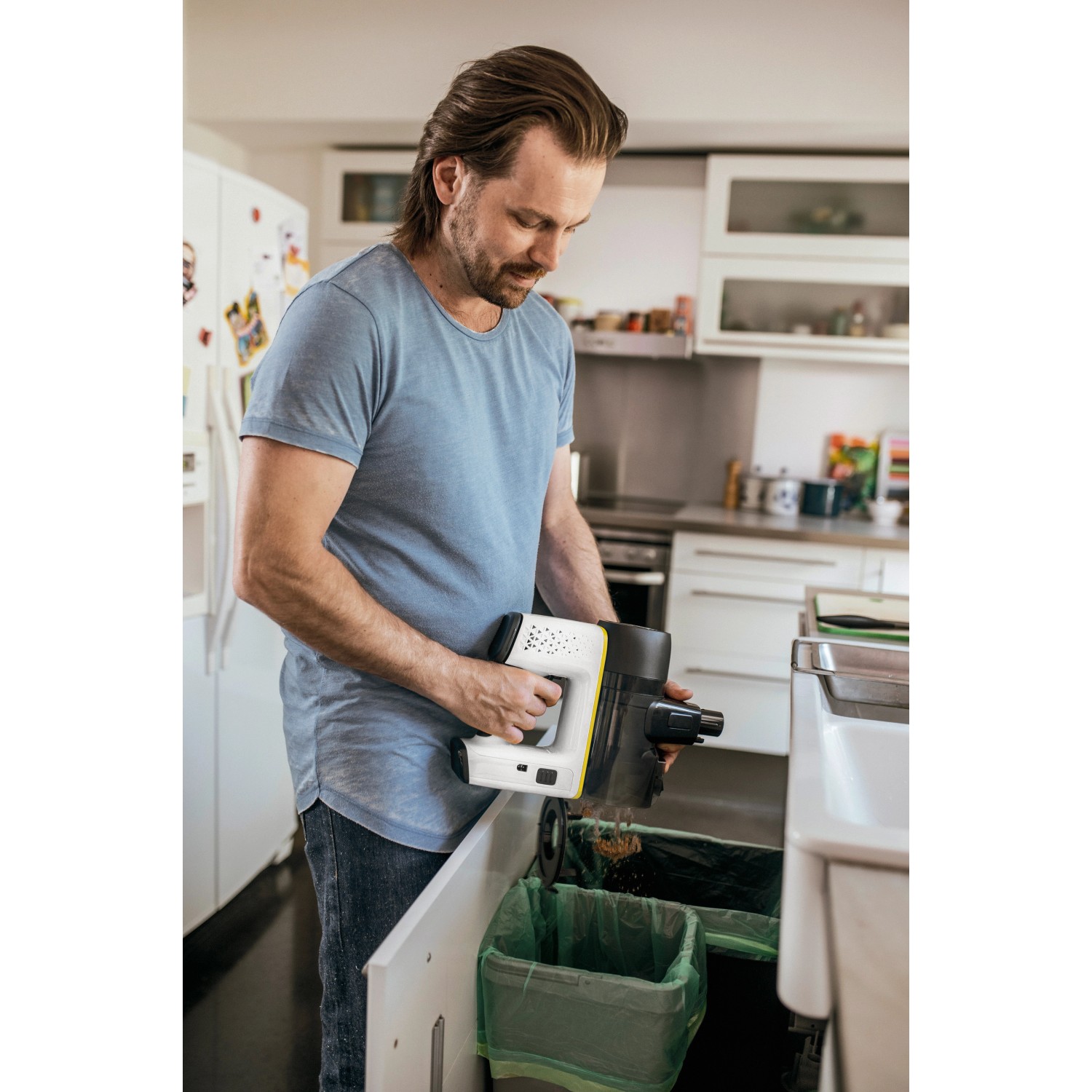 Mann leert Kärcher Akku-Staubsauger VC 6 (2,5 Ah) in Mülleimer. Kabelloser Bodenstaubsauger.