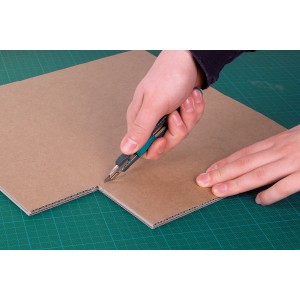 Wolfcraft Abbrechklingenmesser 9 mm schneidet Karton auf grüner Schneidematte.
