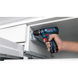 Hand montiert mit Bosch Professional Akku-Bohrschrauber GSR 12V-15 C eine Schubladenschiene in weißem Schrank. Kompaktes Werkzeug.