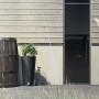 Arves Regentonne Burgund 500 l dunkelbraun in Holzoptik vor Hauswand.