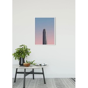 Komar Wandbild Monolith 50x70 cm mit Wolkenkratzer-Motiv im weißen Rahmen.
