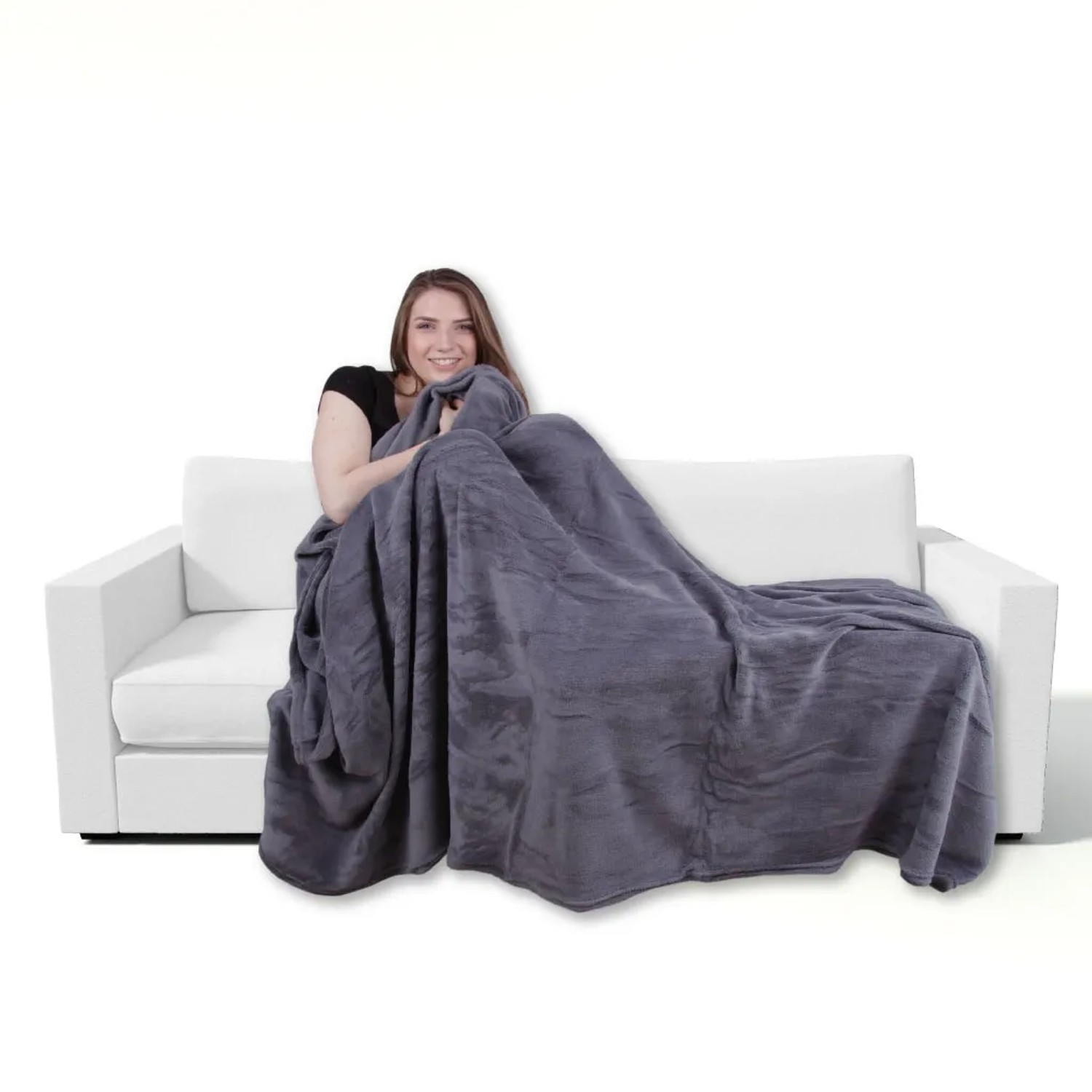 Frau kuschelt in anthrazitfarbener Bestgoodies Mikrofaser Decke (150x200 cm) auf Sofa.