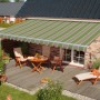 Spettmann Gelenkarmmarkise, 350x250 cm, grün-beige gestreift, montiert über einer Terrasse mit Gartenmöbeln.