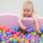 Baby im Bällebad mit LittleTom Bällebadbällen in Pastellfarben (100 Stk., Ø 6cm).