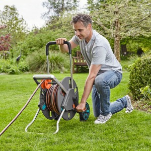 Mann bedient Gardena CleverRoll L Easy Schlauchwagen im Garten.