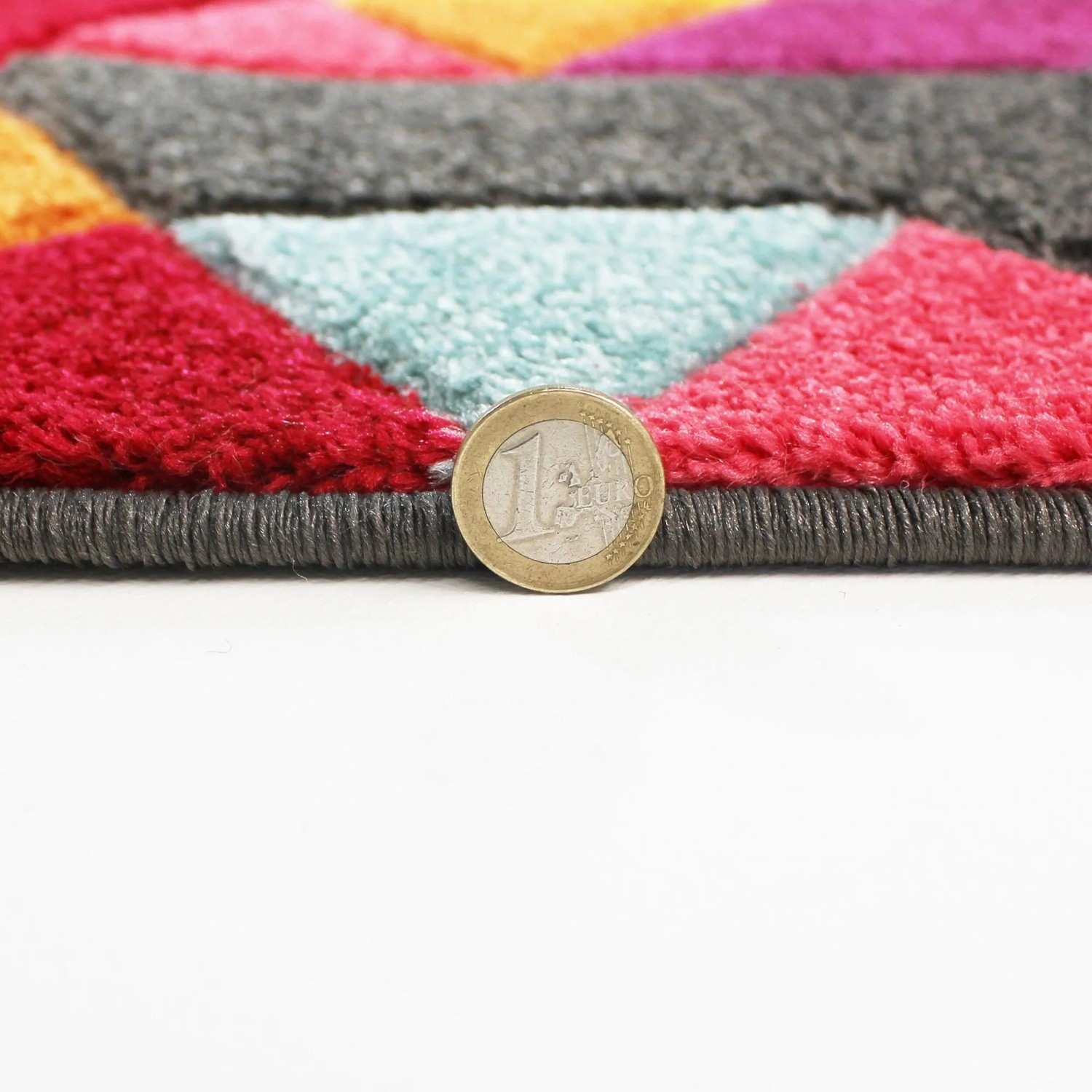 Nahaufnahme des Flair Rugs Kinderteppichs Dynamic. Mehrfarbiges, geometrisches Muster mit 1-Euro-Münze zur Dickenanzeige. Strapazierfähig.