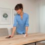 Frau ölt transparente Bondex Arbeitsplatte mit Lappen und Schleifpapier.