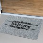 Graue Ripsmatte „Welcome“ 40x60 cm vor einer Tür. Fußmatte für den Innenbereich mit Schriftzug.