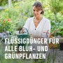 Frau gießt Pflanzen mit Compo Complete Pflanzendünger in grüner Gießkanne.