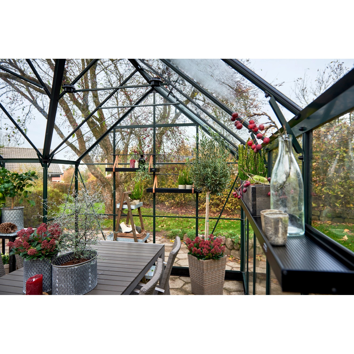 Halls GardenRoom Gewächshaus Set, 12,9 m², grün, mit Fundamentrahmen, eingerichtet mit Tisch und Pflanzen.
