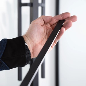 Detailaufnahme: Hand hält schwarzes Alustegenpaar von Loft+Mehr für Glastüren.