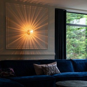Goldene Art Deco Wandleuchte Ayesha mit Glas, montiert im Wohnzimmer.
