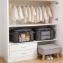 Graue faltbare Aufbewahrungsboxen mit Sichtfenster und Griffen im Kleiderschrank, gefüllt mit Spielzeug und Textilien.