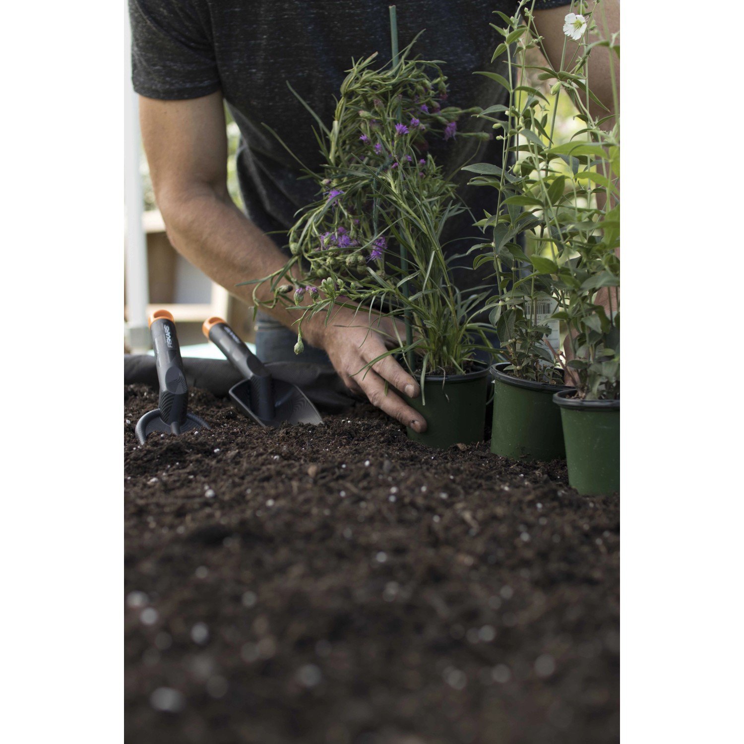 Gartenarbeit mit Fiskars Blumenrechen Solid und Pflanzschaufel beim Einpflanzen von Blumen.
