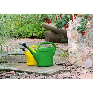 Grüne Geli Gartengießkanne (10 l) neben gelber Gießkanne im Garten.