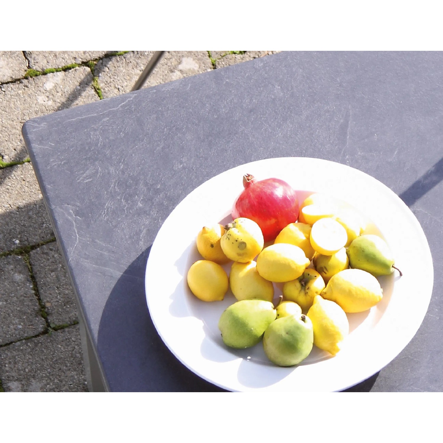 Detailansicht des Acaplan Loft Tisches in Platin-Schiefer mit Obstschale, Teil des Gartenmöbel-Sets.