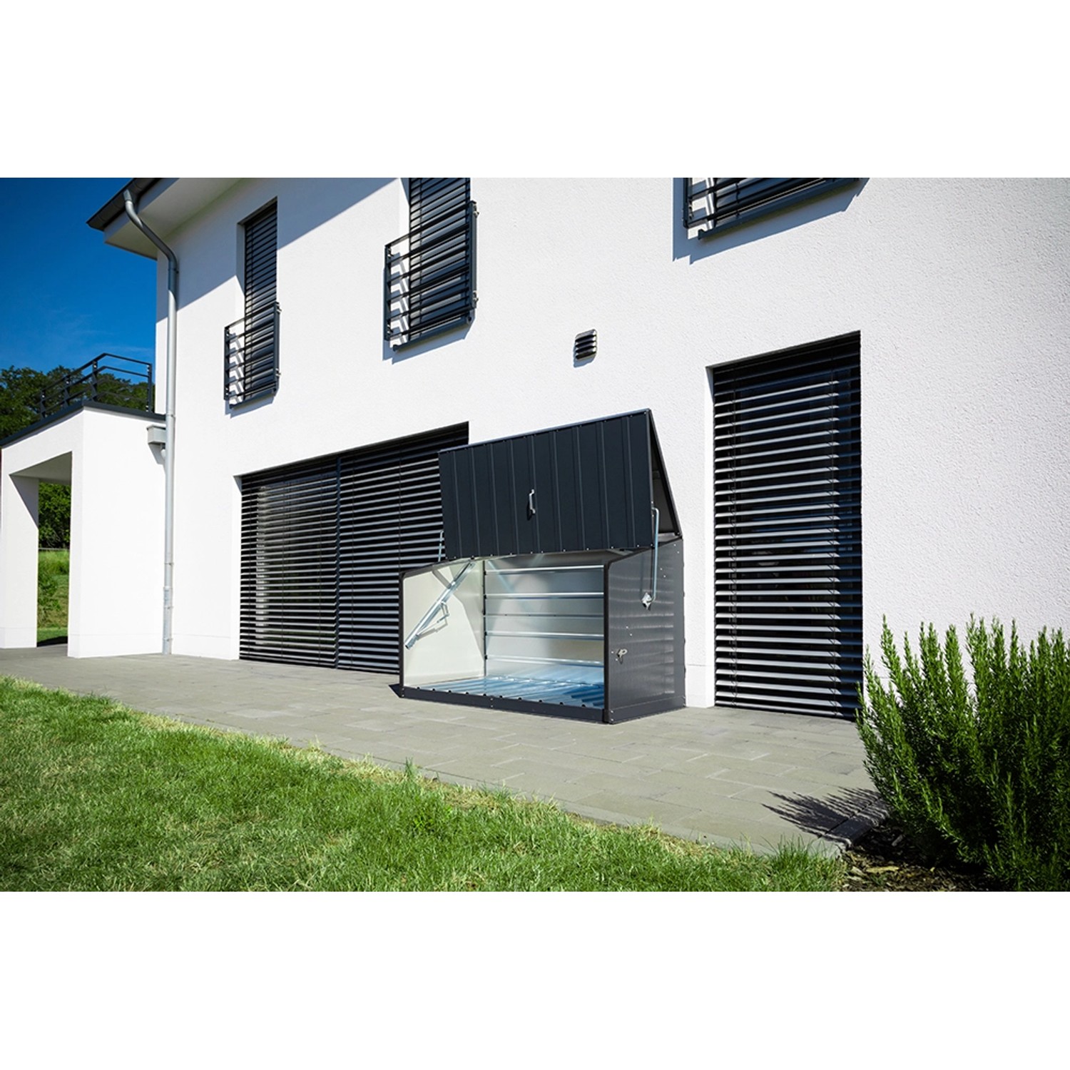 Geöffnete Trimetals Aufbewahrungsbox Storeguard, anthrazit, vor weißer Hauswand. Universelle Metallbox für Garten und Fahrräder.